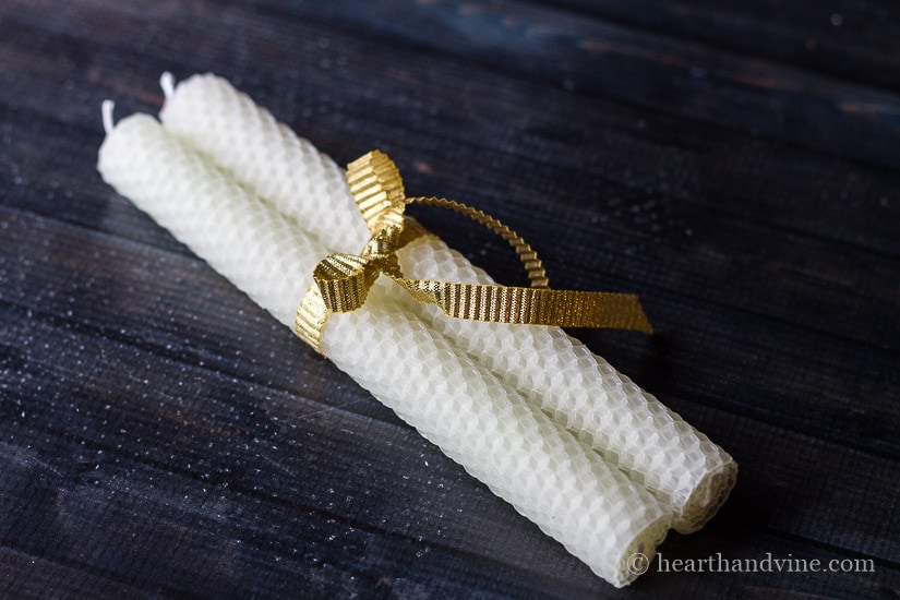 Pair of rolled beeswax candles tied with a gold ribbon.