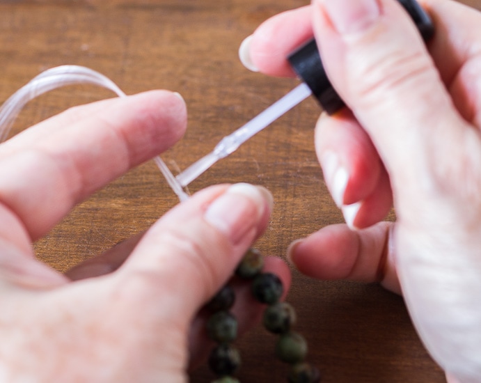 Healing stone bracelets securing knots with nail polish.