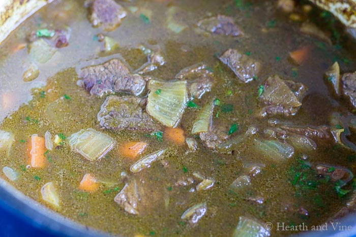 Moroccan beef stew cooking in a pot on the stove.