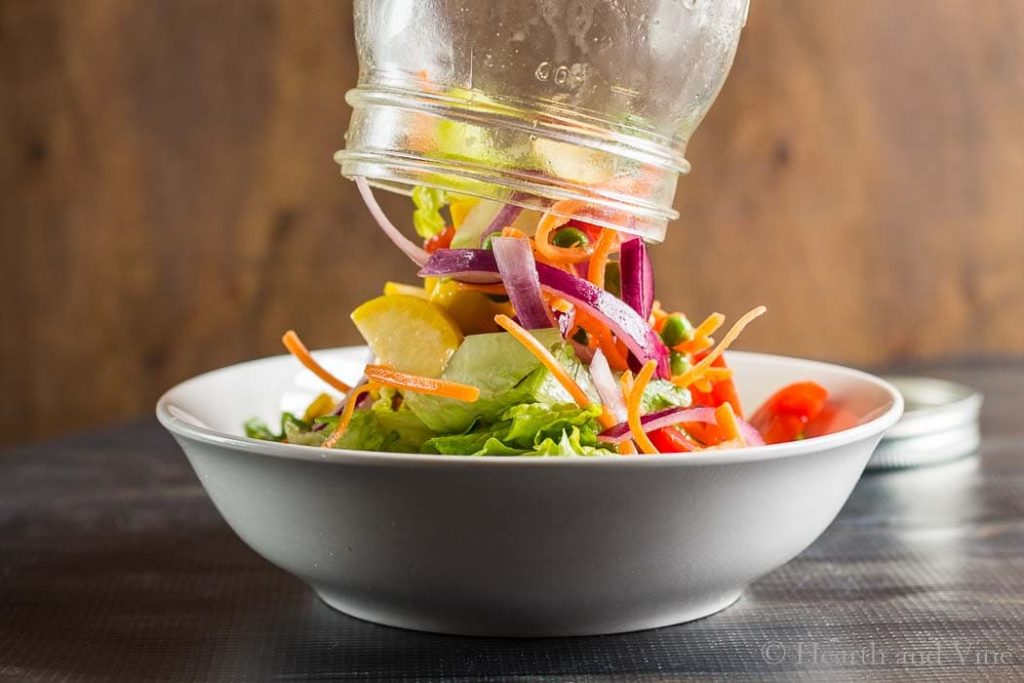 Pouring rainbow jar salad into bowl.