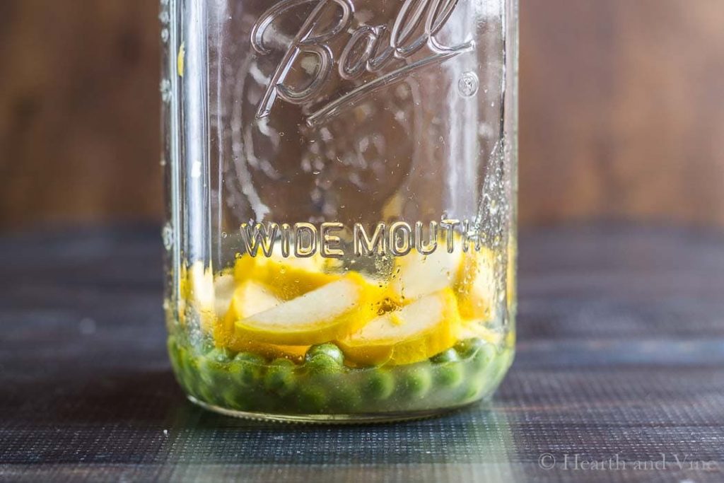 Dressing, peas and squash in bottom of mason jar.