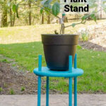 Blue wooden plant stand with a large pot on top.