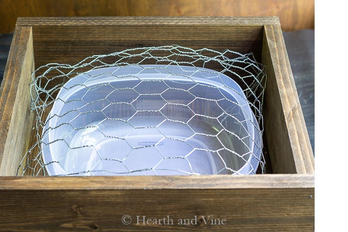 Stained wooden box with plastic tub and chicken wire.