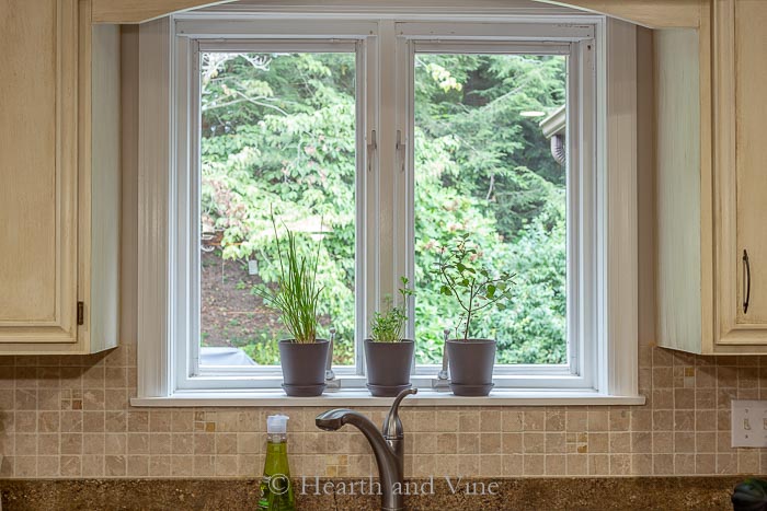 Three pots with herbs on kitchen windowsill