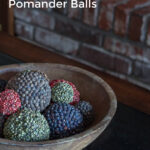 Different colored spice pomander balls in a wooden bowl.