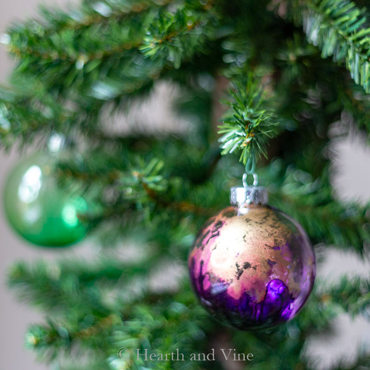 Purple and gold ornament made with alcohol inks on a tree.