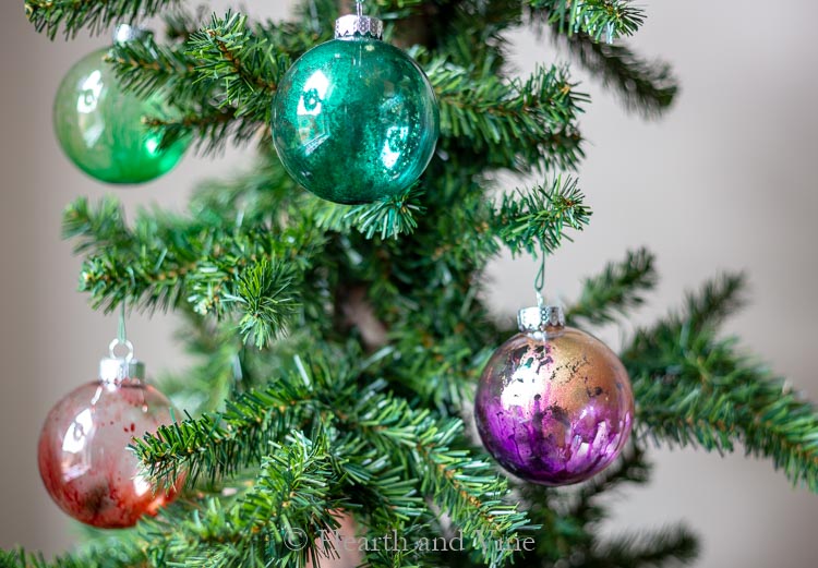 Alcohol ink ornaments hanging on a small Christmas tree.