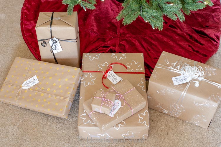 Wrapped gifts under the tree with brown paper decorated with paints.