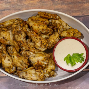 Baked wings in a dish with dipping sauce.
