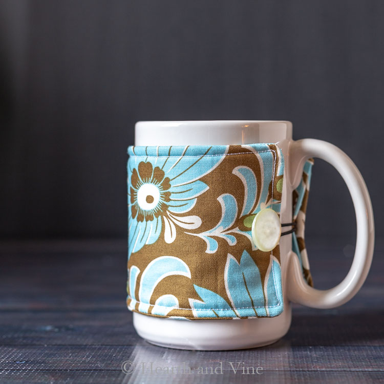 Blue and brown floral fabric coffee sleeve on a white mug.