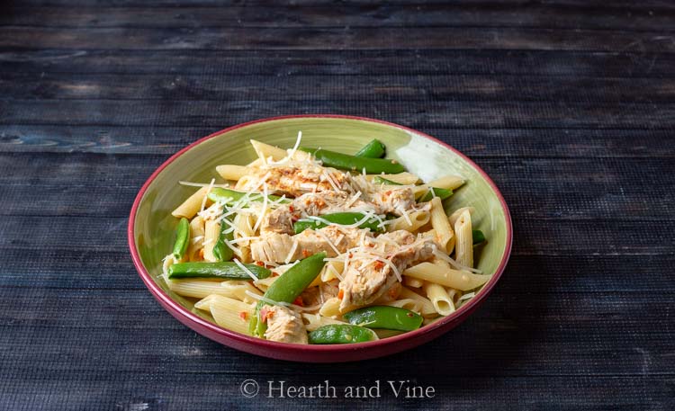 Bowl of red pepper cream sauce pasta with chicken and snap peas