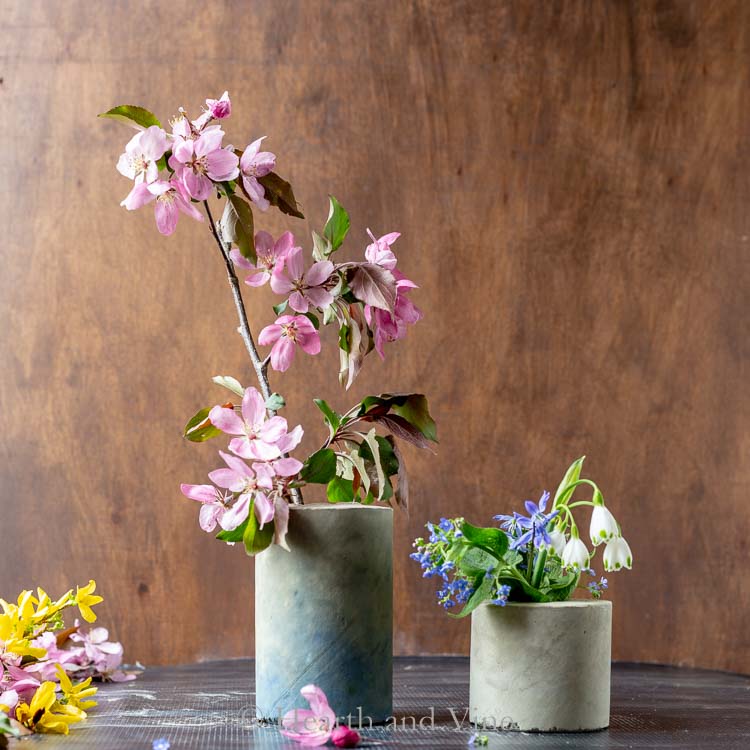 Two concrete vases with flowers inside