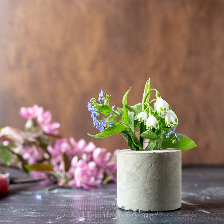 Small concrete vase with blue and white flowers