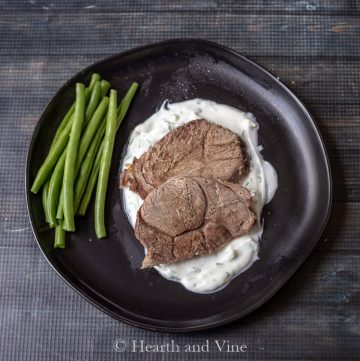 Sliced slow cooker leg of lamb with tzatiki sauce and green beans