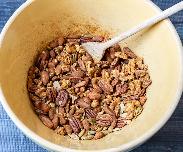 Mixing roasted nuts with spices in a large bowl