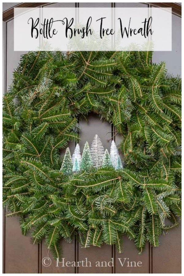 Evergreen wreath with little village of bottle brush tree inside.