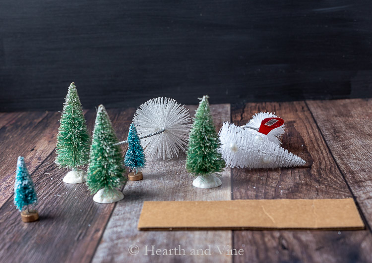 Different sizes and color of bottle brush trees and piece of cardboard