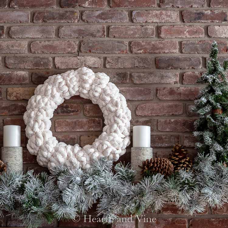 Decorated white Christmas mantel with a while wreath and flocked greenery