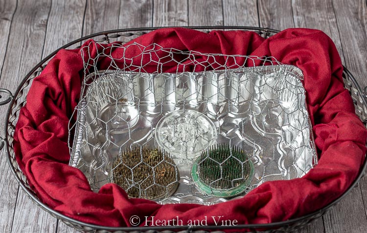 Wire basket with red fabric, foil tin, flower frogs and chicken wire
