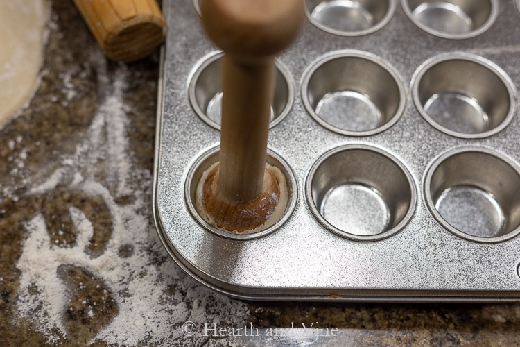 Pressing dough into mini muffin cups with dowel