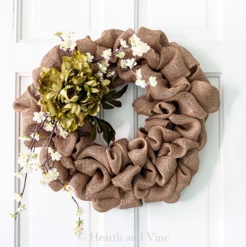 Burlap wreath with flowers on white door