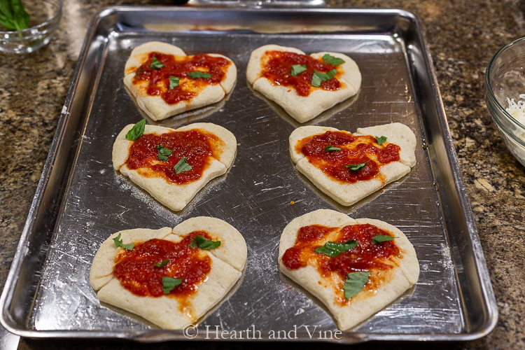 Mini heart shaped pizzas with marinara and basil