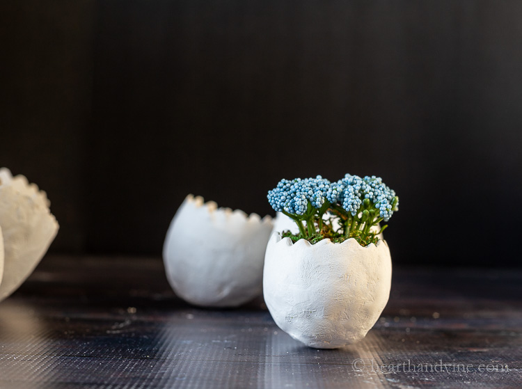 Blue faux flowers in egg planter