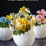 Three small clay egg with faux flowers inside.