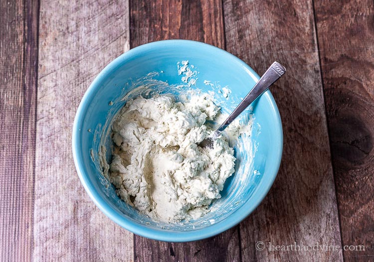 Mixing ingredients for blue cheese spread in a large blue bowl.