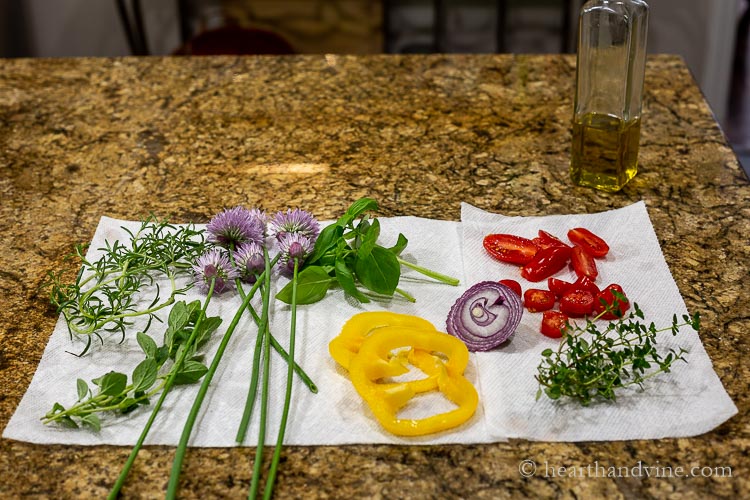 Fresh herbs and vegetables drying on a paper towel.