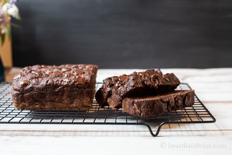 Chocolate zucchini bread partially sliced on a cooling rack.