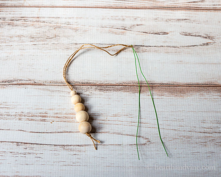 Five wood beads threaded onto twine with a wire.