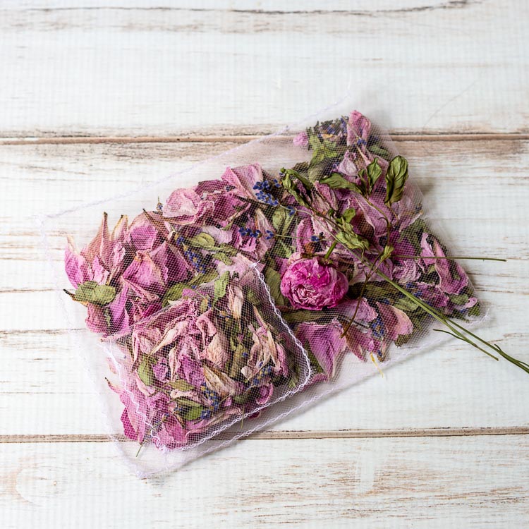 Two flower petal sachets stack on top of each other with a few dried whole flowers on top.