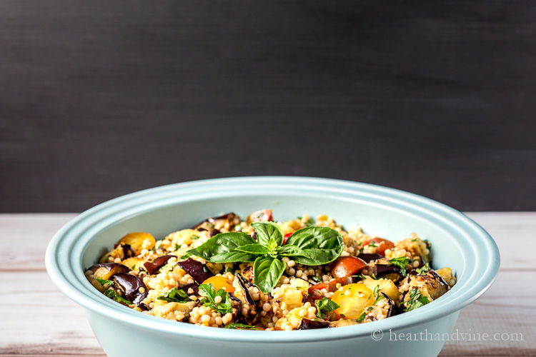 Close view of grilled eggplant salad in a large blue serving bowl.