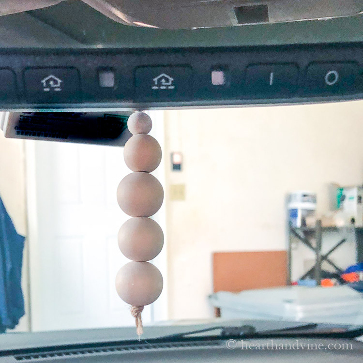 Finished wood bead diffuser hanging from car rearview mirror.