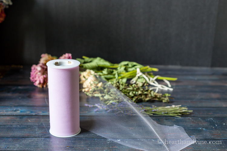 Lilac colored spool of tulle in front of dried flowers.