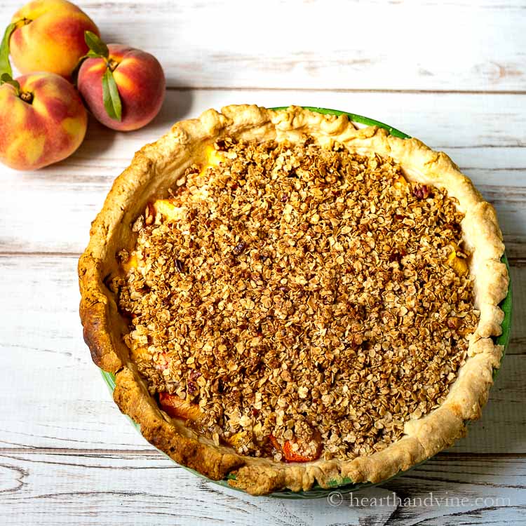 Peach pie crumble and three fresh peaches.