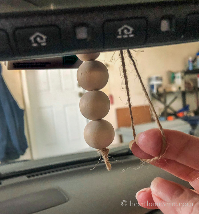 Hanging the wood bead diffuser on the rearview mirror in a car.