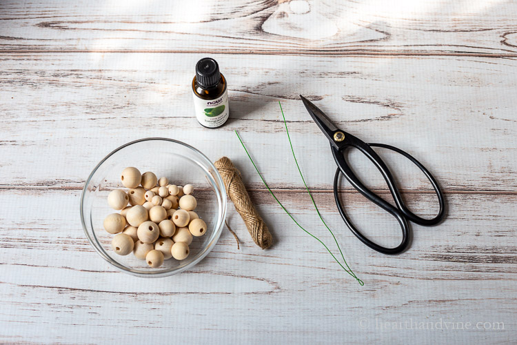 Wooden beads, twine, wire, scissors and a bottle of essential oil.