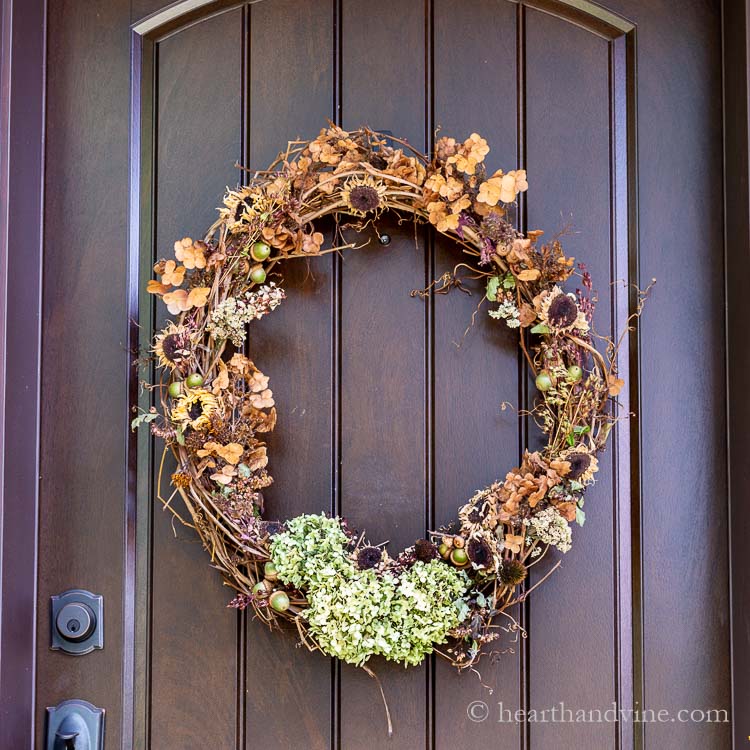 A natural fall wreath hanging on the front door from backyard plants, trees and other natural elements.