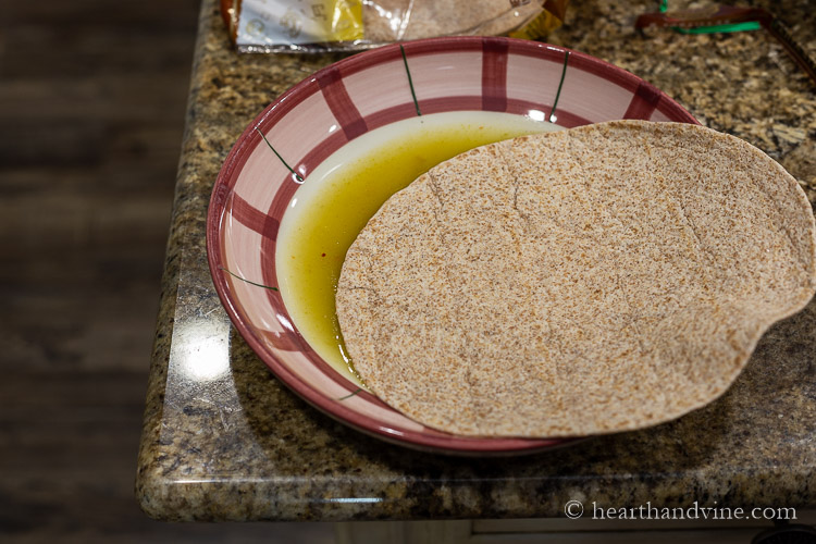 Dipping whole wheat tortillas in enchilada sauce.