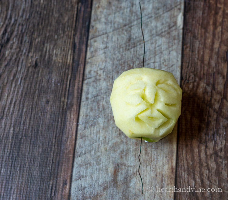 Carved apple head with wire through the middle for hanging.