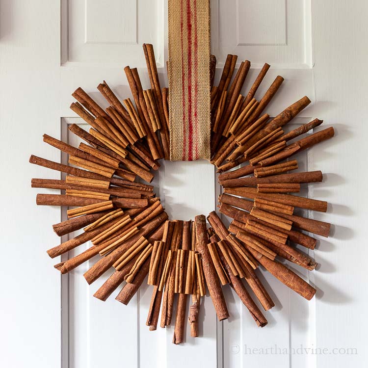 Star shaped cinnamon stick wreath hung a door with a stripped ribbon.