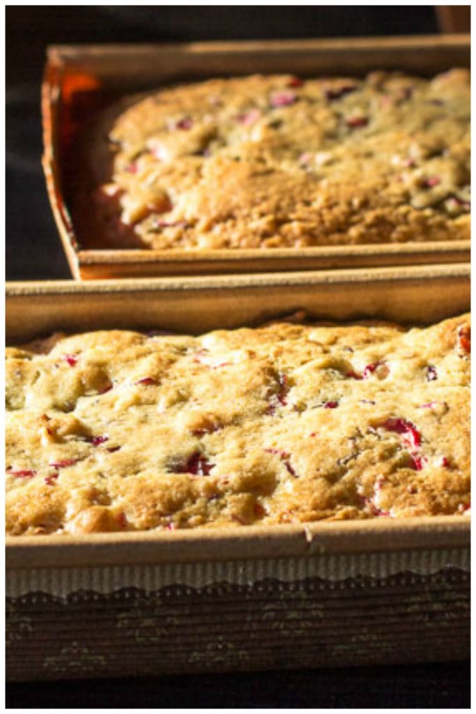 Two loaves of cranberry orange bread in decorative paper loaf pans.