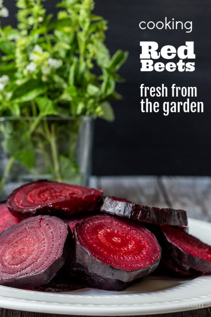A close up look at sliced roasted red beets on a plate next to a vase with basil cuttings.