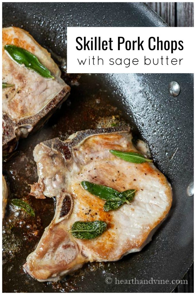 A close of up a pork chop in a skillet with sage and brown butter sauce.
