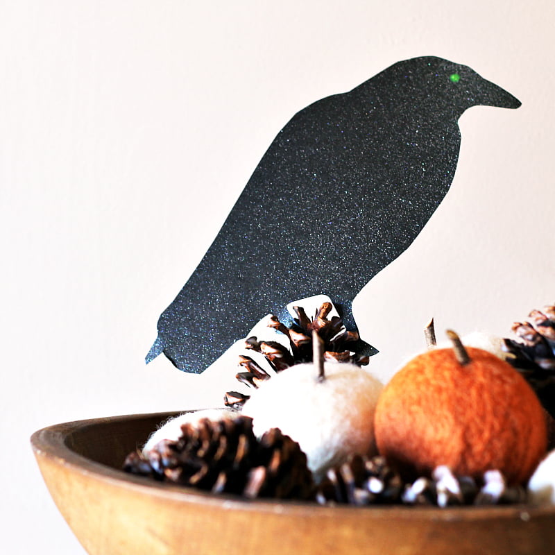 Scary bird silhouette on a bowl of pine cones and pumpkins.