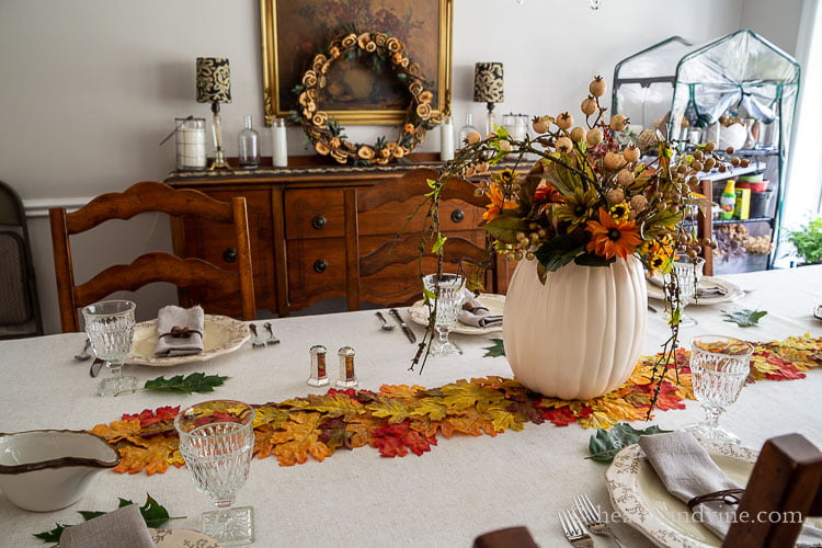 Side view of decorated Thanksgiving tablescape and dining room buffet with dried fruit wreath.