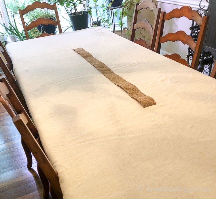 Burlap ribbon in the center of a large dining room table.