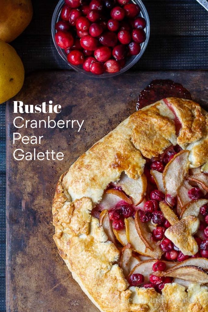 A partial view of a cranberry pear galette on a baking stone.